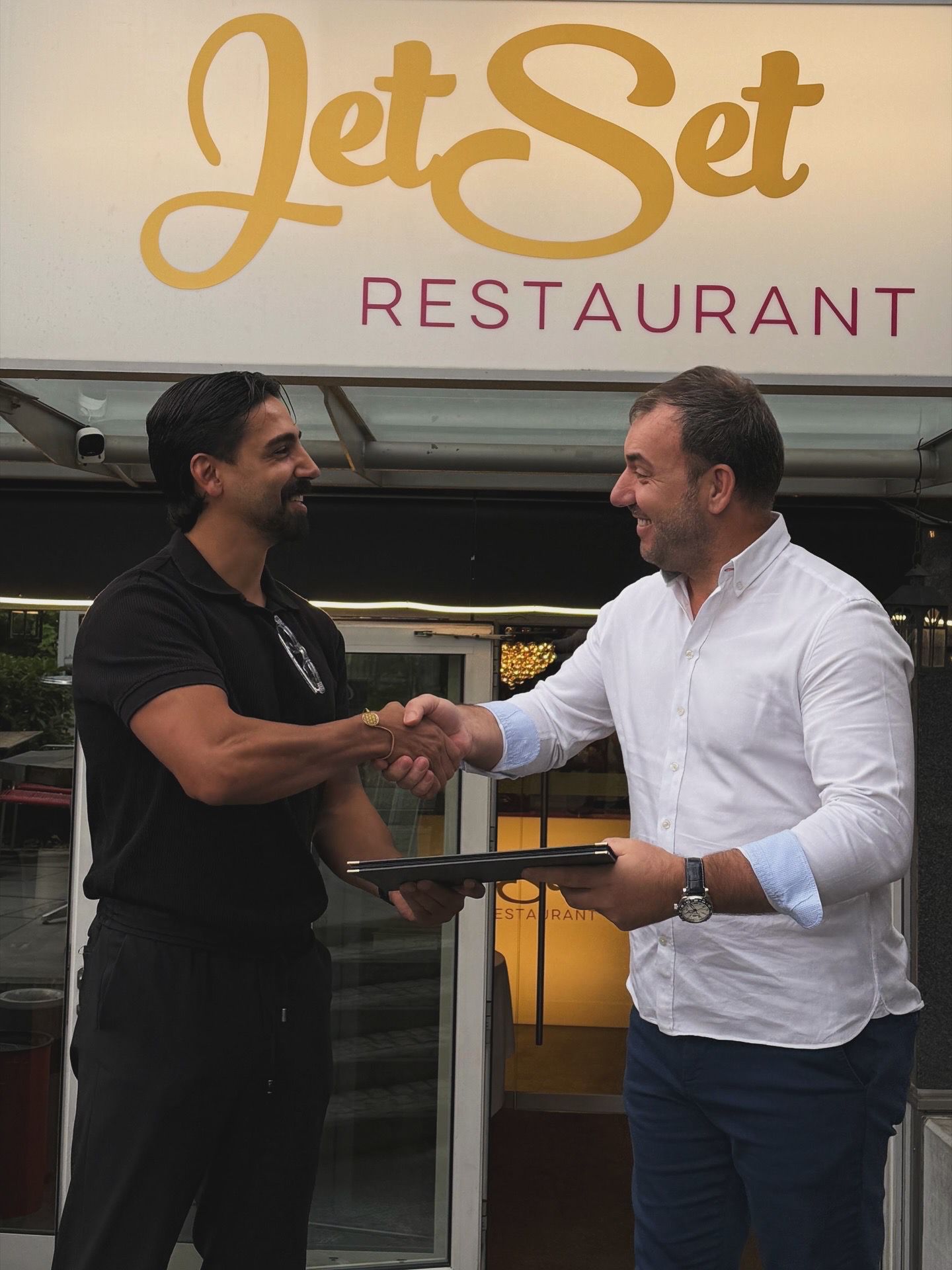 Persönliche Übergabe der gedruckten Speisekarte vor dem Eingang des Jet Set Restaurants